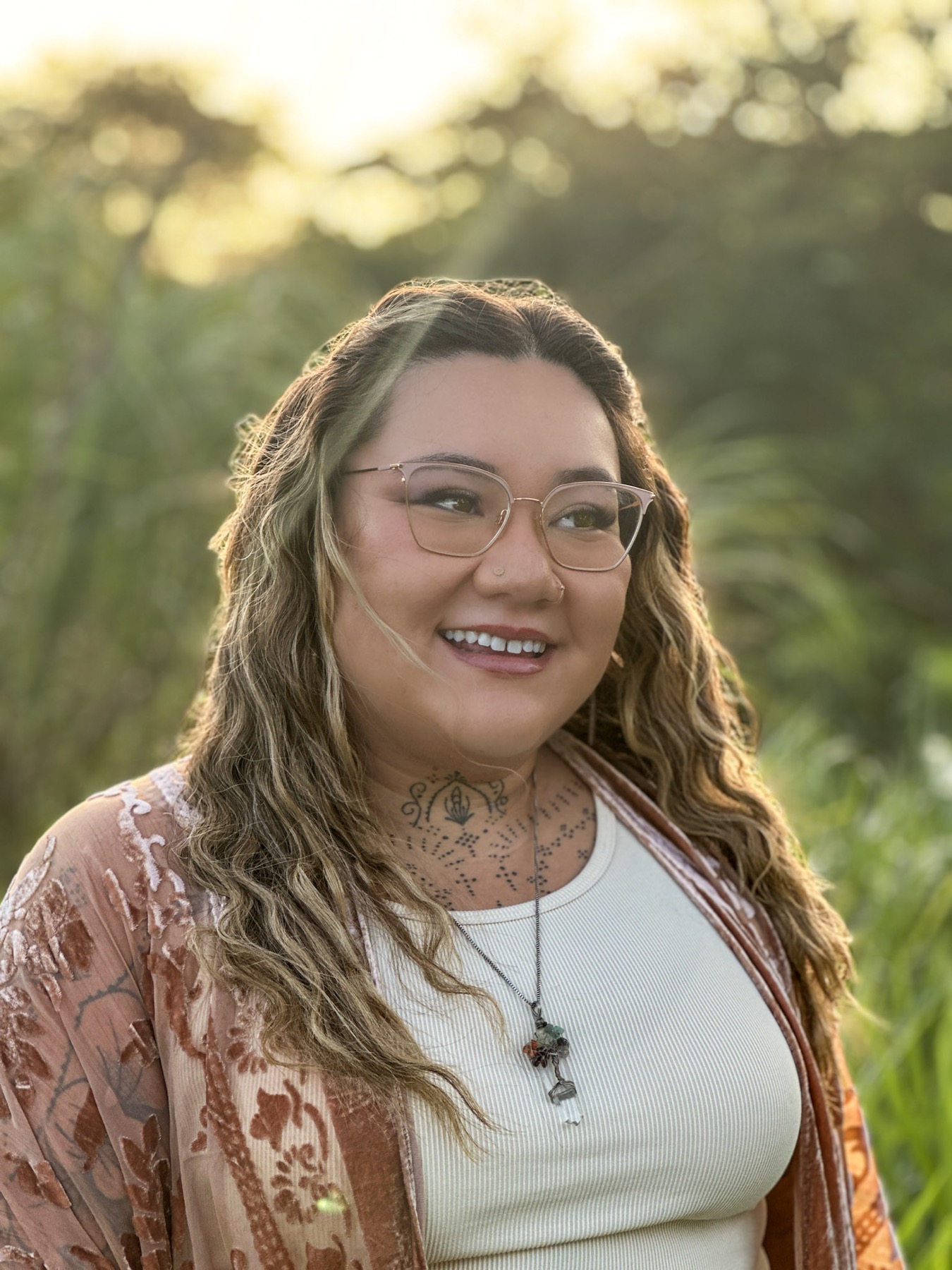 Xsana Saphire standing in tall golden grass, warm late light across her face